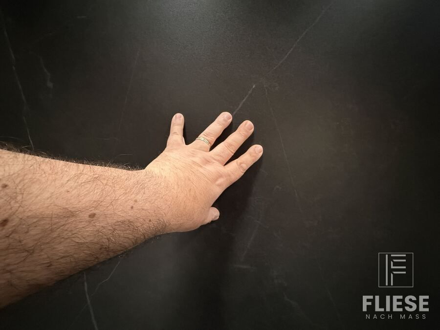 Hand auf der Oberfläche der Nero Marquina zur Größeneinordnung